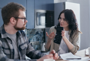 An image of a woman sitting on a table and holding a calculator 