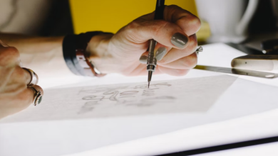 A person drawing logo designs on paper.