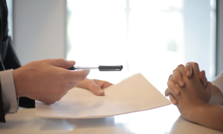 An image of a man giving a contract to a woman for signing